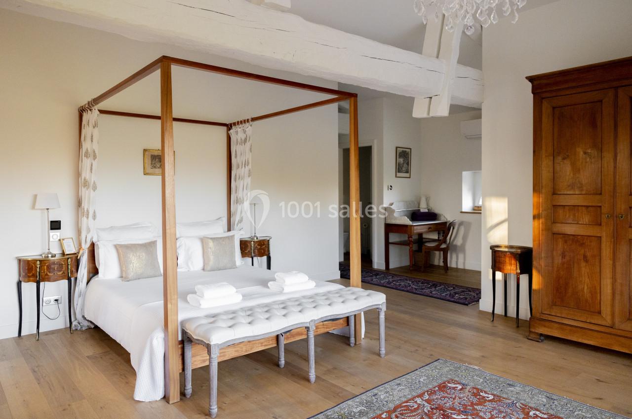 Suite Cèdre Chambre lumineuse avec lit à baldaquin, meubles en bois, poutres apparentes et décoration élégante.