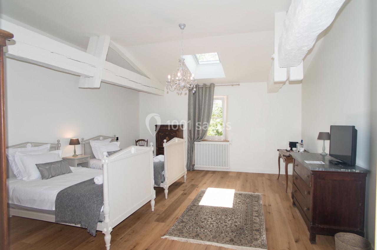 Suite Cyprès Chambre lumineuse avec deux lits simples, parquet en bois, meubles anciens et plafond avec poutres apparentes.