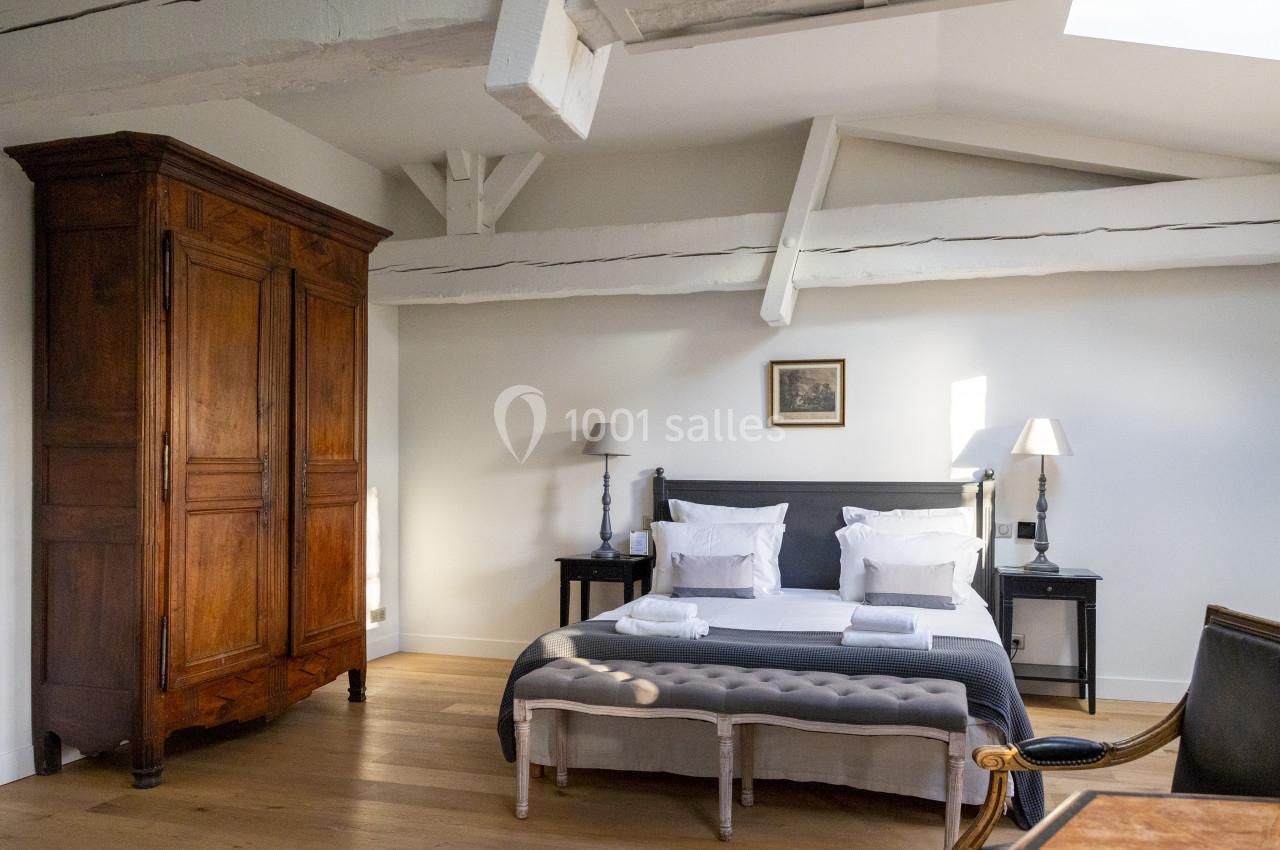 Suite Olivier Chambre lumineuse avec lit double, armoire en bois, poutres apparentes et parquet clair.