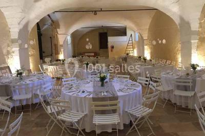 Plan de table sur un chevalet près de l'entrée d'une salle éclairée par des guirlandes lumineuses, ambiance festive.