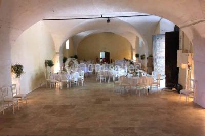 Plan de table sur un chevalet près de l'entrée d'une salle éclairée par des guirlandes lumineuses, ambiance festive.