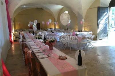 Plan de table sur un chevalet près de l'entrée d'une salle éclairée par des guirlandes lumineuses, ambiance festive.