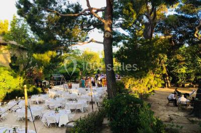 Plan de table sur un chevalet près de l'entrée d'une salle éclairée par des guirlandes lumineuses, ambiance festive.