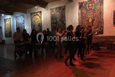 Plan de table sur un chevalet près de l'entrée d'une salle éclairée par des guirlandes lumineuses, ambiance festive.