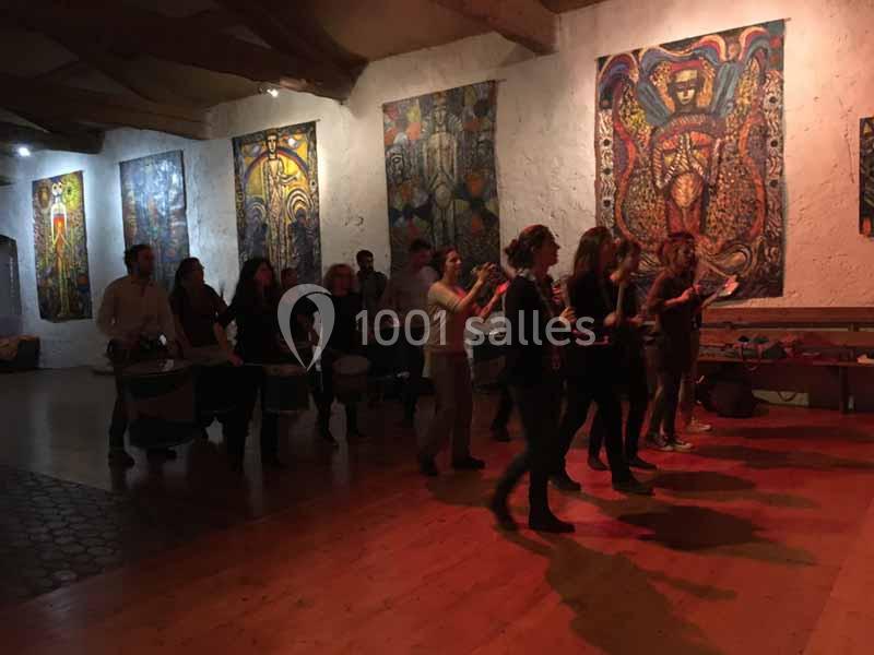 Un groupe de personnes joue des percussions dans une salle décorée de grandes œuvres d'art colorées.