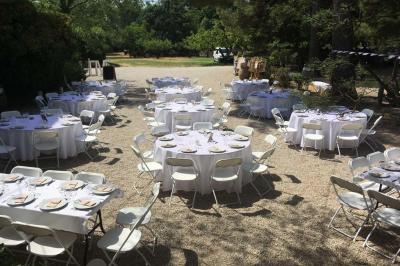 Plan de table sur un chevalet près de l'entrée d'une salle éclairée par des guirlandes lumineuses, ambiance festive.