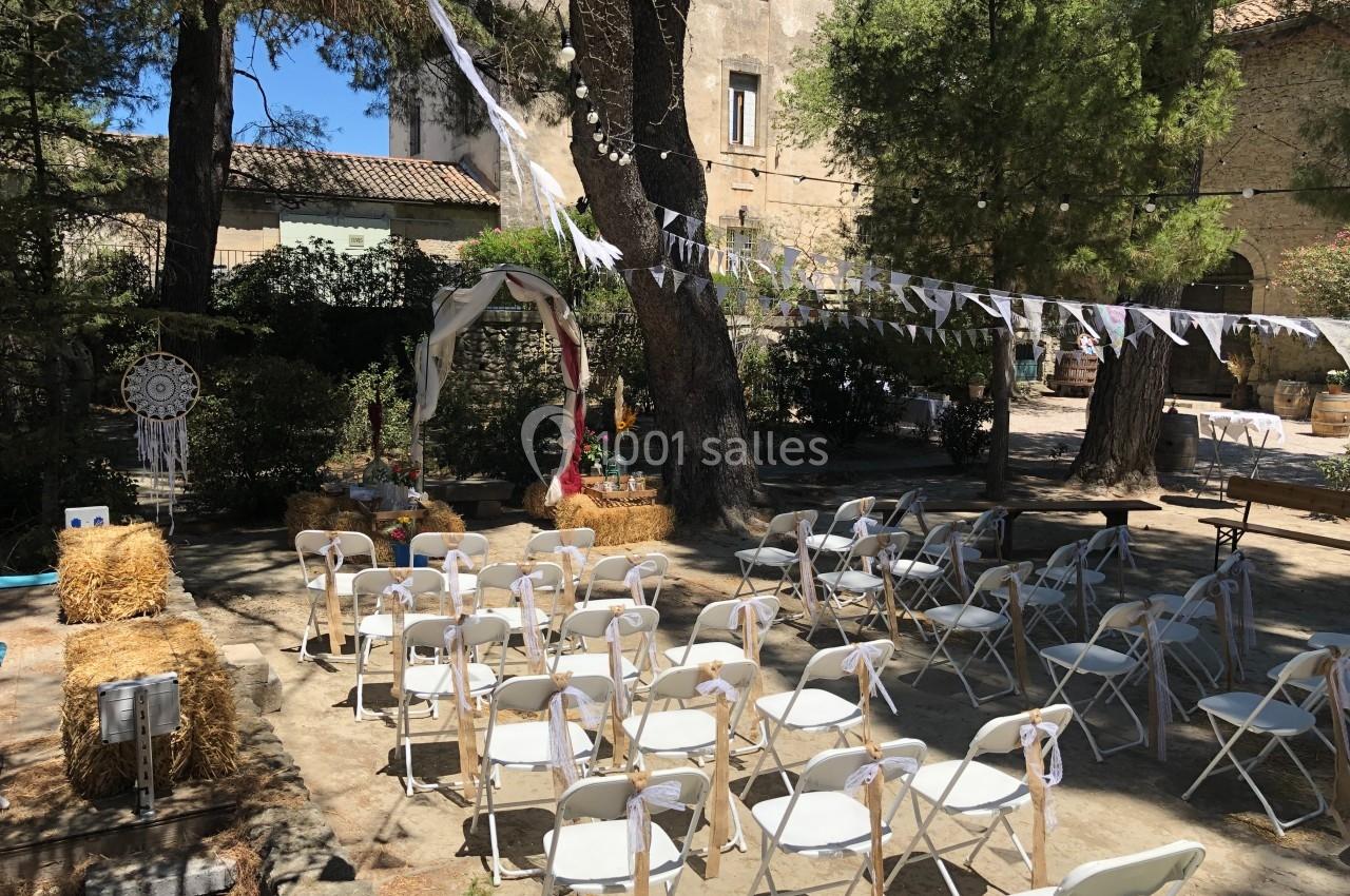 Chaises blanches disposées en extérieur pour une cérémonie, entourées de bottes de foin et de décorations champêtres.