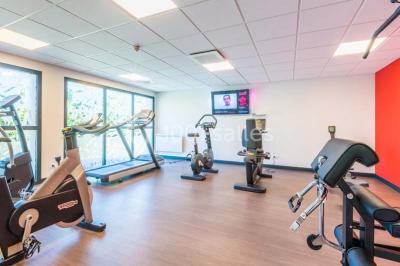 Salle de sport lumineuse avec tapis de course, vélos d'appartement et équipements de musculation.