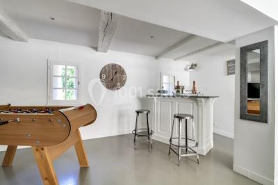 Salle de séjour lumineuse avec canapé, baby-foot, table basse en bois, télévision et décoration moderne.