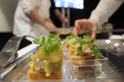 Chambre moderne avec lit double, bureau équipé, grande fenêtre avec vue sur les toits et éclairage suspendu.