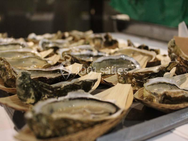 Huîtres ouvertes présentées sur des supports en feuilles naturelles, prêtes à être consommées.