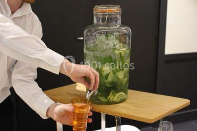 Chambre moderne avec lit double, bureau équipé, grande fenêtre avec vue sur les toits et éclairage suspendu.