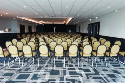 Chambre moderne avec lit double, bureau équipé, grande fenêtre avec vue sur les toits et éclairage suspendu.