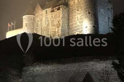 Chambre moderne avec lit double, bureau équipé, grande fenêtre avec vue sur les toits et éclairage suspendu.