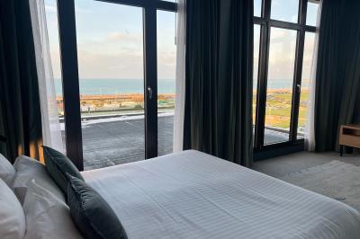 Chambre moderne avec lit double, bureau équipé, grande fenêtre avec vue sur les toits et éclairage suspendu.