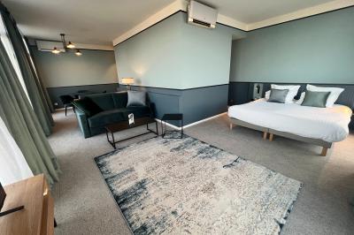 Chambre moderne avec lit double, bureau équipé, grande fenêtre avec vue sur les toits et éclairage suspendu.