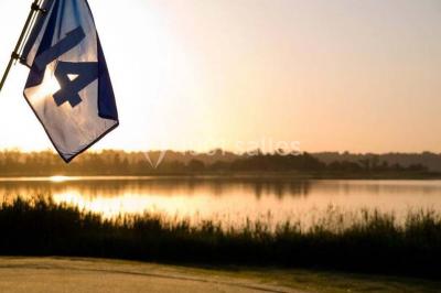 Chambre lumineuse avec lit double, deux tables de chevet, lampes murales, fauteuil et rideaux à motifs floraux.