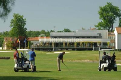 Chambre lumineuse avec lit double, deux tables de chevet, lampes murales, fauteuil et rideaux à motifs floraux.
