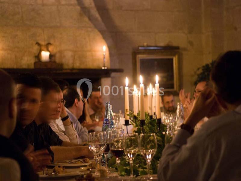 Des convives discutent autour d'une table élégamment dressée avec des chandeliers allumés dans une ambiance chaleureuse.