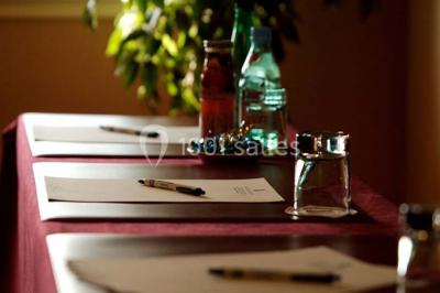 Chambre lumineuse avec lit double, deux tables de chevet, lampes murales, fauteuil et rideaux à motifs floraux.