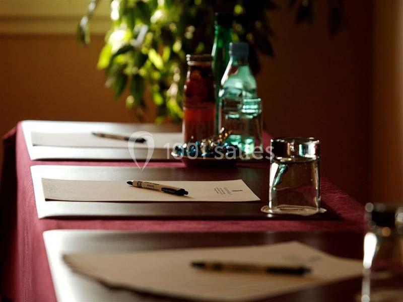 Des tables avec des feuilles, stylos, bouteilles d'eau et bonbons, prêtes pour une réunion ou un atelier.