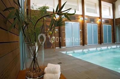 Chambre lumineuse avec lit double, deux tables de chevet, lampes murales, fauteuil et rideaux à motifs floraux.