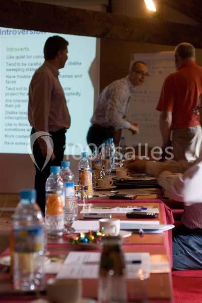 Des personnes discutent dans une salle de réunion avec une table garnie de bouteilles d'eau et de documents au premier plan.