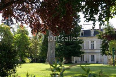 Chambre lumineuse avec lit double, deux tables de chevet, lampes murales, fauteuil et rideaux à motifs floraux.