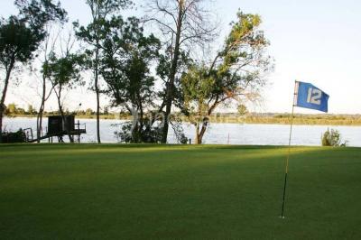 Chambre lumineuse avec lit double, deux tables de chevet, lampes murales, fauteuil et rideaux à motifs floraux.
