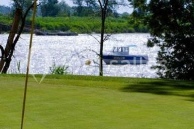 Chambre lumineuse avec lit double, deux tables de chevet, lampes murales, fauteuil et rideaux à motifs floraux.
