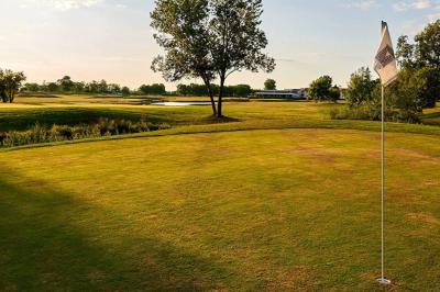 Chambre lumineuse avec lit double, deux tables de chevet, lampes murales, fauteuil et rideaux à motifs floraux.