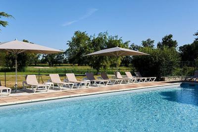 Chambre lumineuse avec lit double, deux tables de chevet, lampes murales, fauteuil et rideaux à motifs floraux.