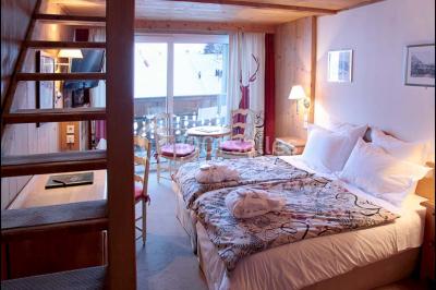 Chalet en bois éclairé de nuit avec balcons, toit enneigé et enseigne ’La Tapiaz’.