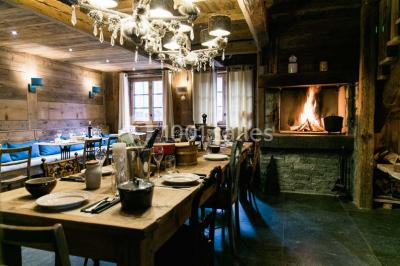 Chalet en bois éclairé de nuit avec balcons, toit enneigé et enseigne ’La Tapiaz’.