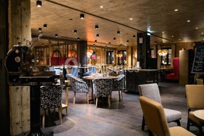 Chalet en bois éclairé de nuit avec balcons, toit enneigé et enseigne ’La Tapiaz’.