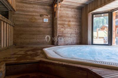 Chalet en bois éclairé de nuit avec balcons, toit enneigé et enseigne ’La Tapiaz’.