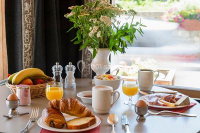 Chalet en bois éclairé de nuit avec balcons, toit enneigé et enseigne ’La Tapiaz’.