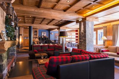 Chalet en bois éclairé de nuit avec balcons, toit enneigé et enseigne ’La Tapiaz’.