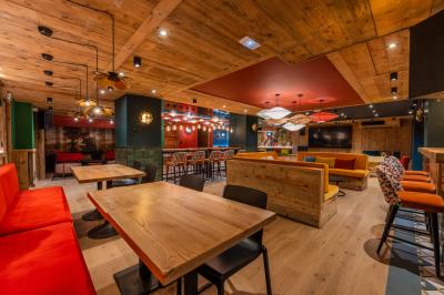 Chalet en bois éclairé de nuit avec balcons, toit enneigé et enseigne ’La Tapiaz’.