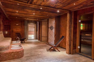 Chalet en bois éclairé de nuit avec balcons, toit enneigé et enseigne ’La Tapiaz’.