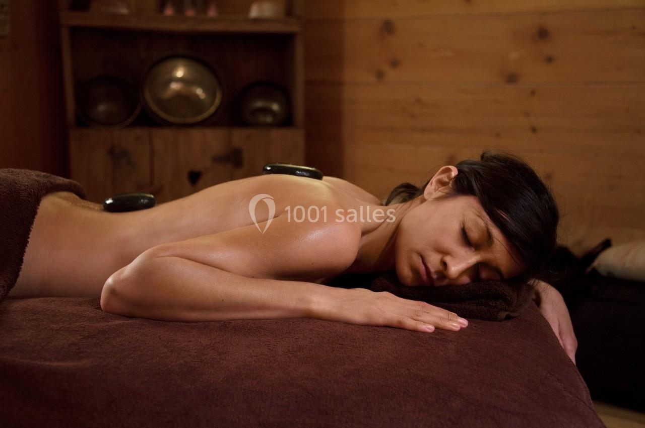 Femme allongée sur le ventre dans un spa, recevant un soin avec des pierres chaudes sur le dos.