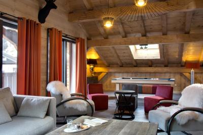 Chalet en bois éclairé de nuit avec balcons, toit enneigé et enseigne ’La Tapiaz’.