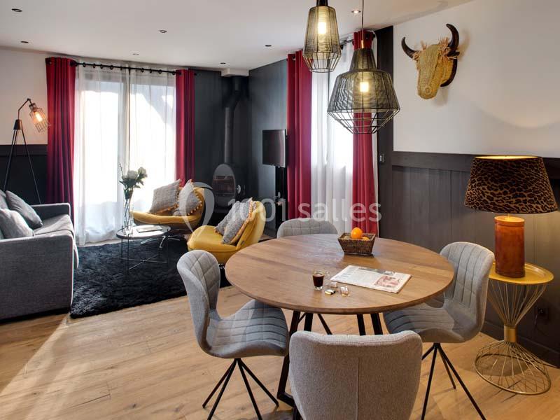 Salle de séjour moderne avec coin repas, canapé, fauteuils jaunes, rideaux rouges et décoration murale.