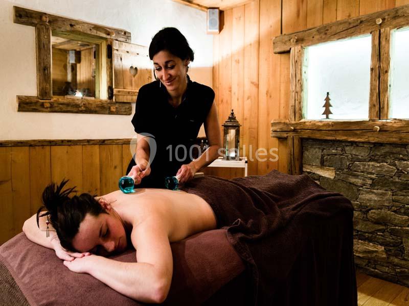 Une femme reçoit un massage avec des ventouses dans une salle en bois à l'ambiance chaleureuse.