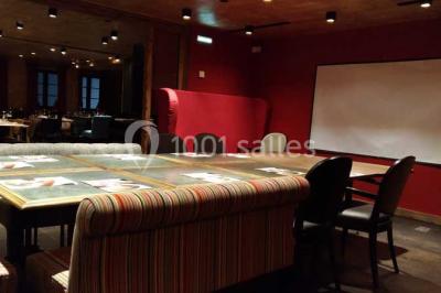 Une réunion d'équipe se déroule dans une salle moderne avec écran de présentation et éclairage design.