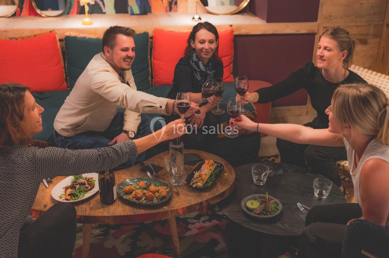 Un groupe de personnes trinque avec des verres de vin autour d'une table garnie de plats variés dans un cadre chaleureux.