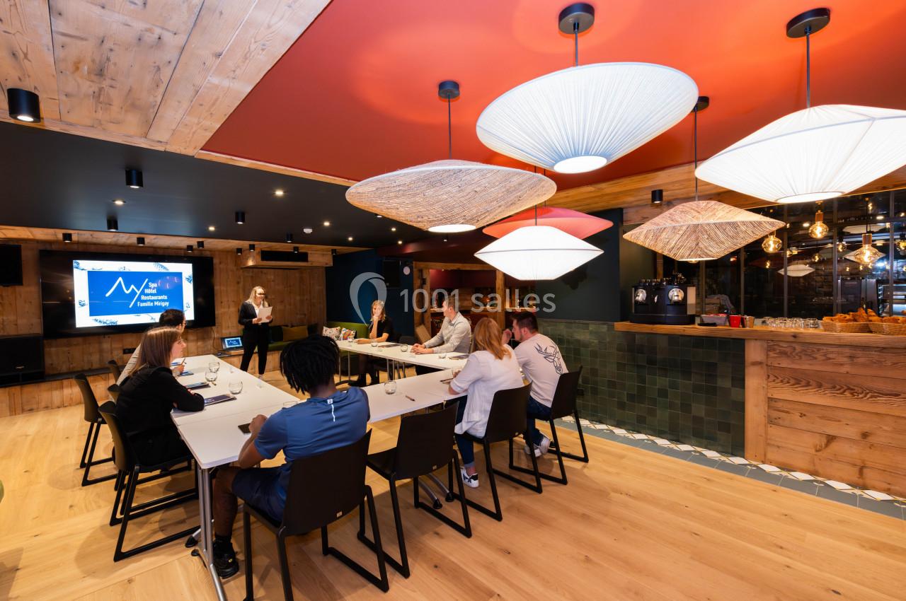 Une réunion d'équipe se déroule dans une salle moderne avec écran de présentation et éclairage design.