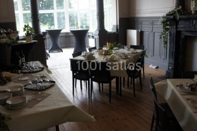 Grande maison en briques rouges avec deux tours, entourée de pelouse et de voitures garées devant.