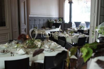 Grande maison en briques rouges avec deux tours, entourée de pelouse et de voitures garées devant.
