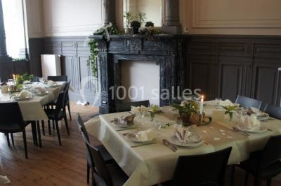 Grande maison en briques rouges avec deux tours, entourée de pelouse et de voitures garées devant.